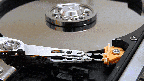 GIF animation showing the internal workings of a hard drive. The disk is spinning and the read write heads moving.drive