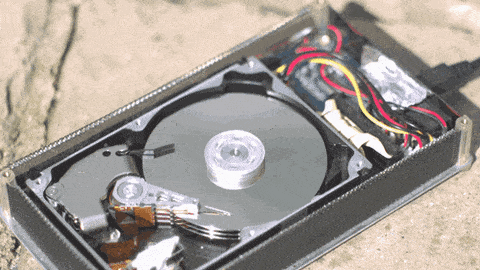 Hard disk drive with the top removed revealing the disk spinning and the read/write heads moving across the disk.